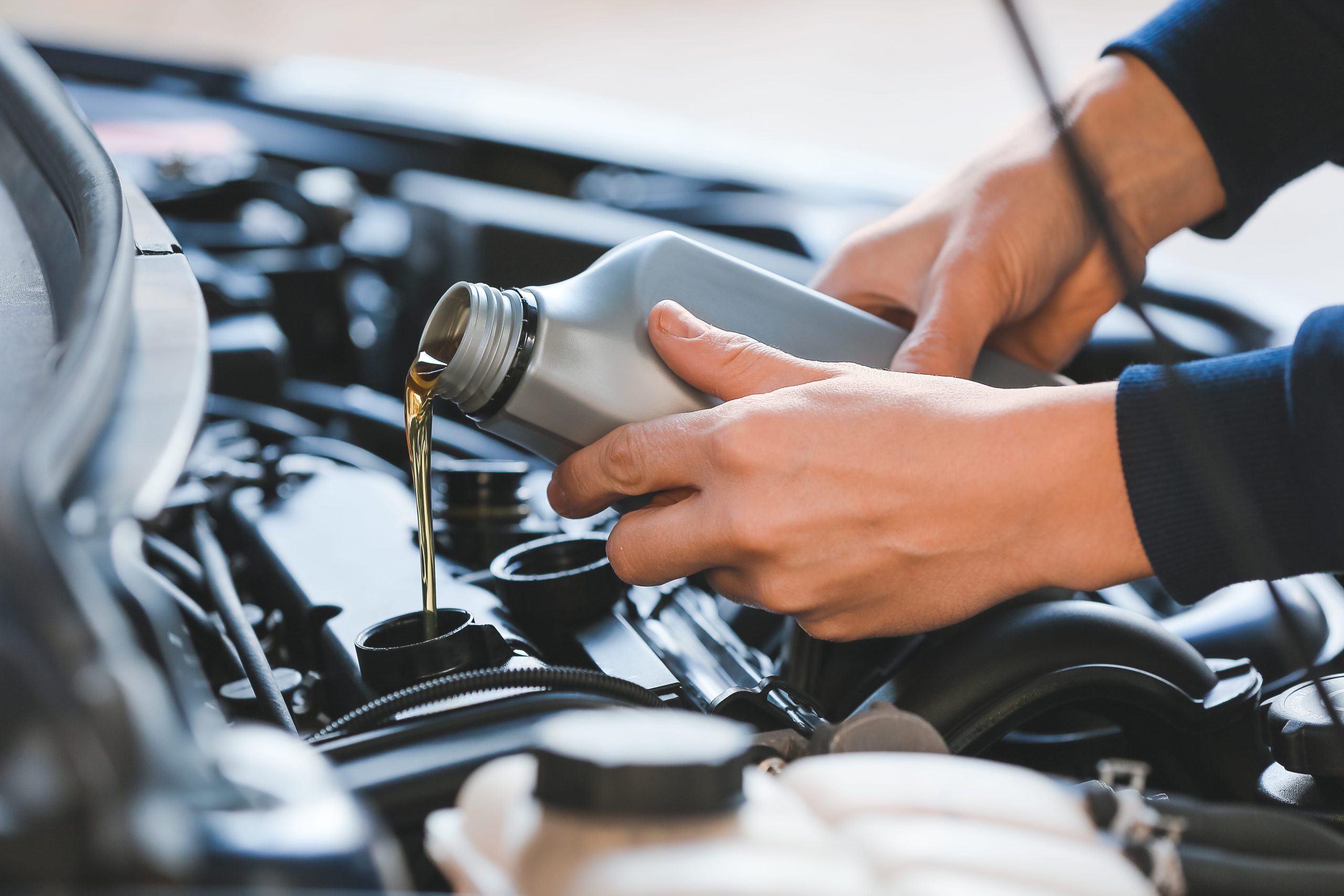 mechanic pouring transmission oil into a car