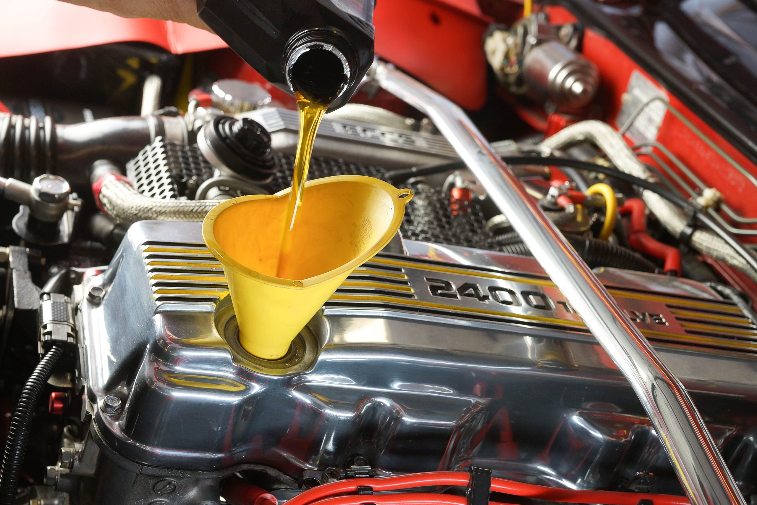 Mechanic adding transmission fluid to a car's engine through a funnel
