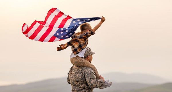 Man in military with boy on shoulders waving American flag