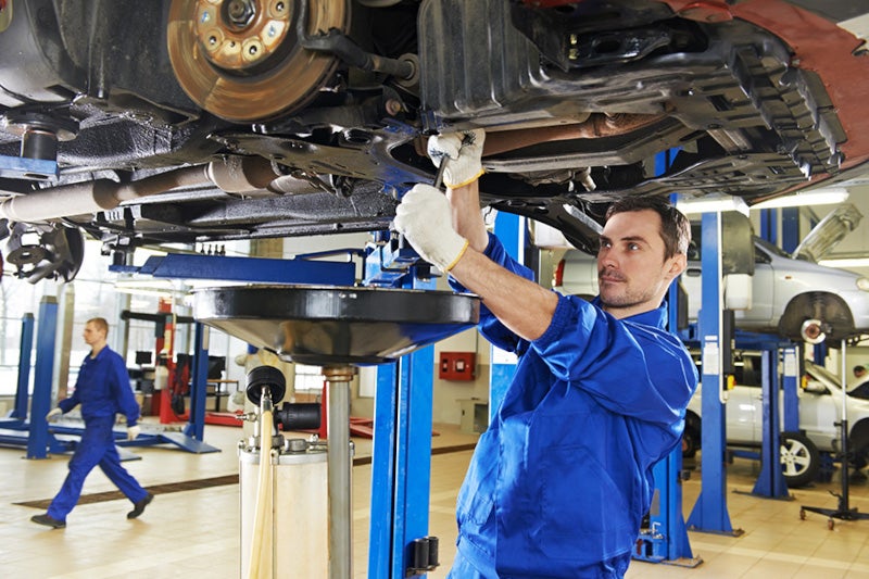 Mechanic changing oil under a lifted car