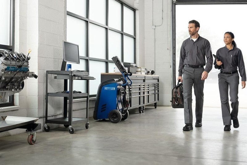 Two technicians walking through shop with equipment 